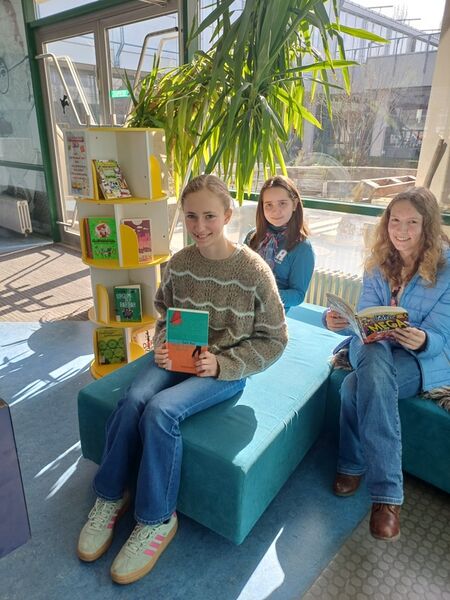 TMG Bücherschrank: drei Lesescouts mit Büchern auf dem Sofa